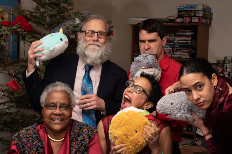 A mixed-race family posing in front of a Christmas tree