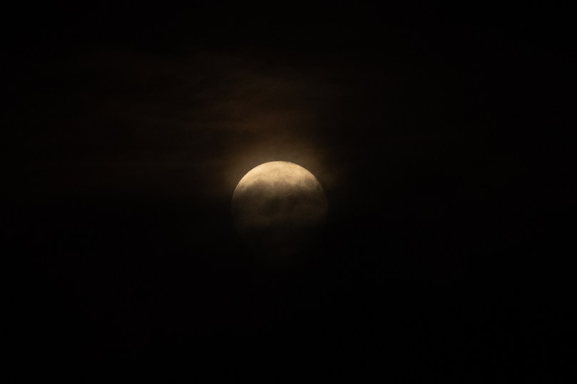 Moon still emerging from behind clouds